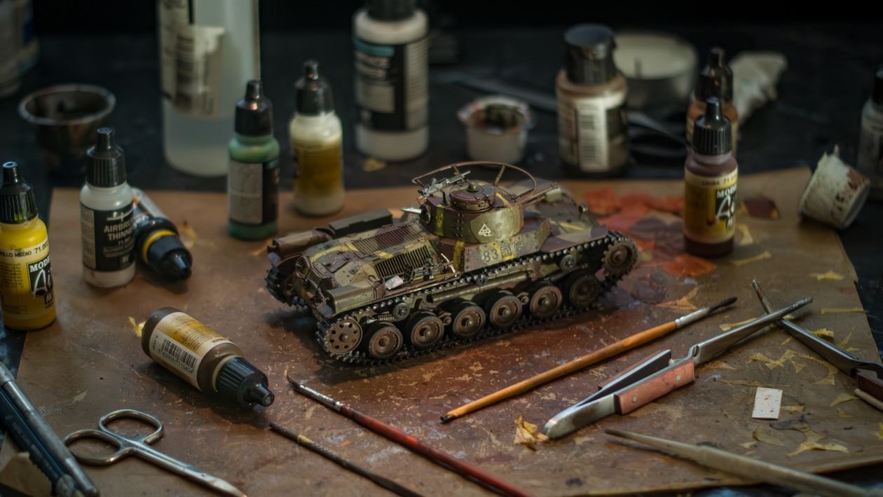 A detailed painted model surrounded by brushes and paints on a hobby workbench