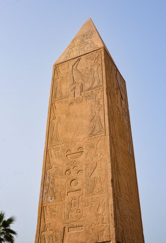 Stone obelisk covered in Egyptian hieroglyphs against a clear blue sky